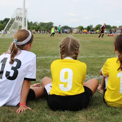 Children in jerseys looking onto a soccer field.