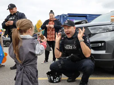 Police officer entertaining a child in a costume.