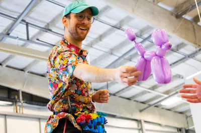 Person holding a purple balloon animal.