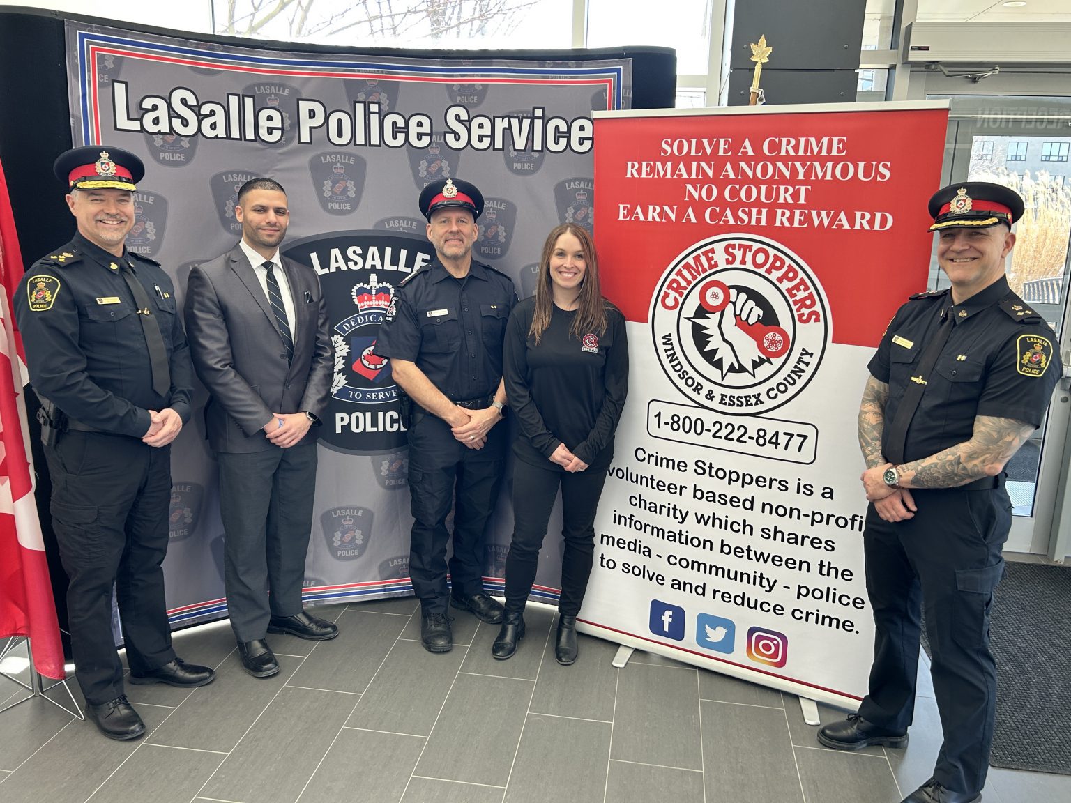 three uniformed police officers and two civilians standing in front of signs