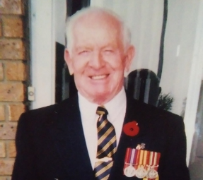 William Hazael smiling wearing a suit and a poppy with medals