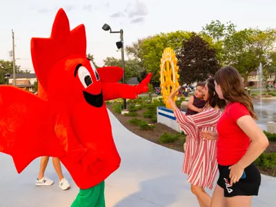 Maple leaf mascot waving at people.