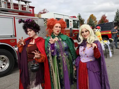 Three women in witch costumes posing in front of a truck.