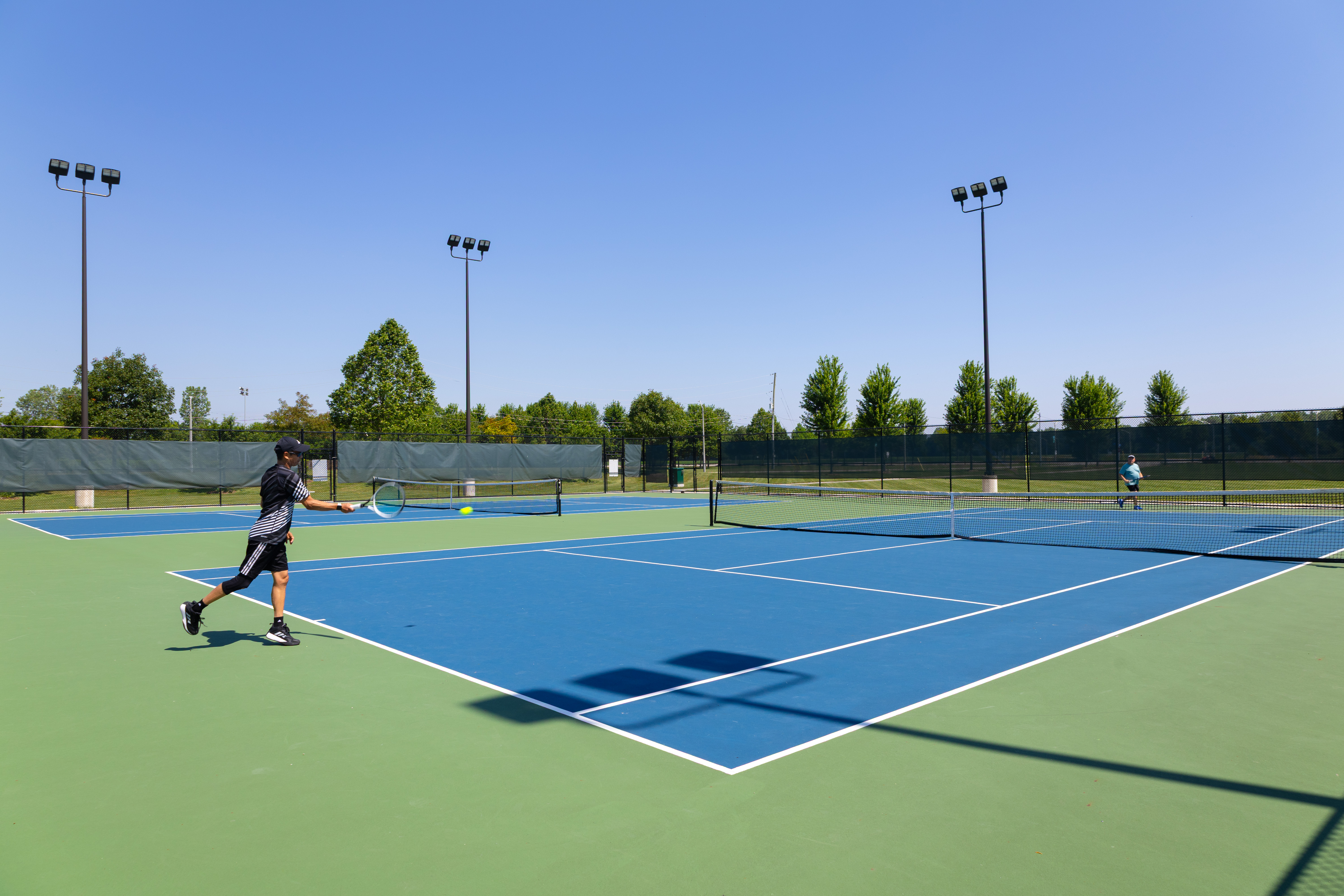 People playing tennis at Vollmer Centre's outdoor courts.