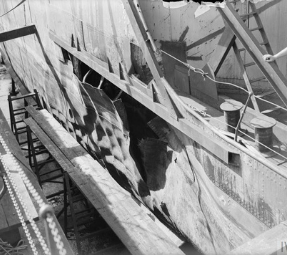 A hull of a ship showing damage after an attack in black and white