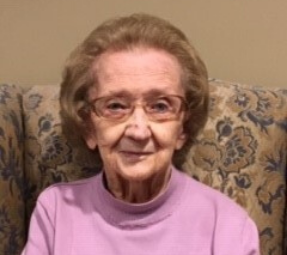 Frances Parr sitting on a couch smiling