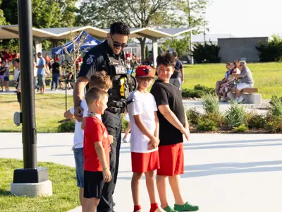 Smiling police officer standing with children.