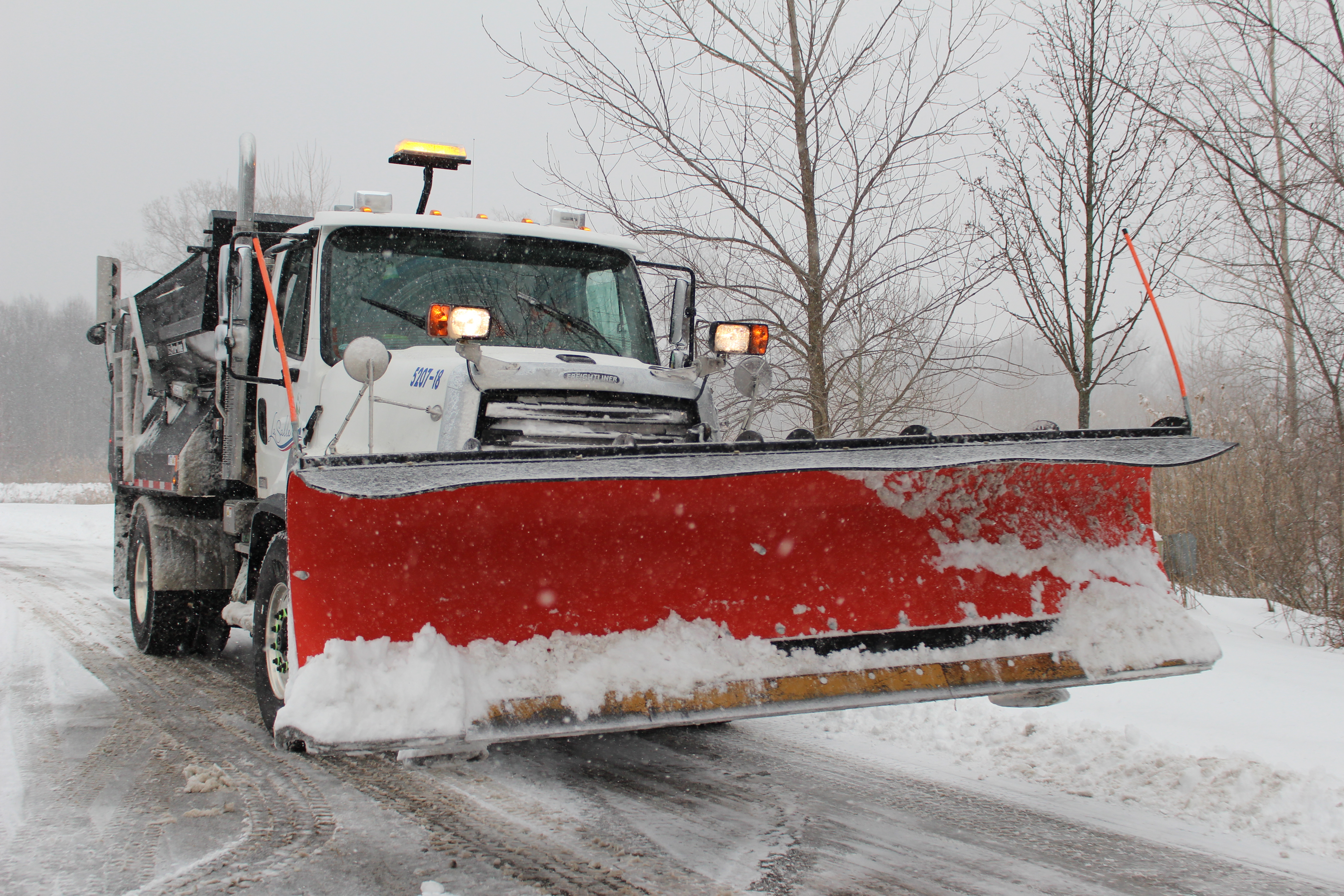 Large snowplow driving on a road.