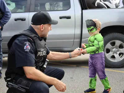 Police officer fist bumping a child in a costume.