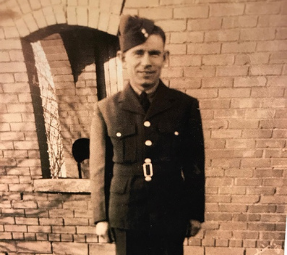 Young Enos Howson standing in front of a brick wall wearing his uniform