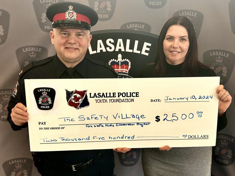 police officer and woman holding up a large donation cheque