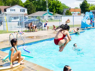 Children jumping into a pool.